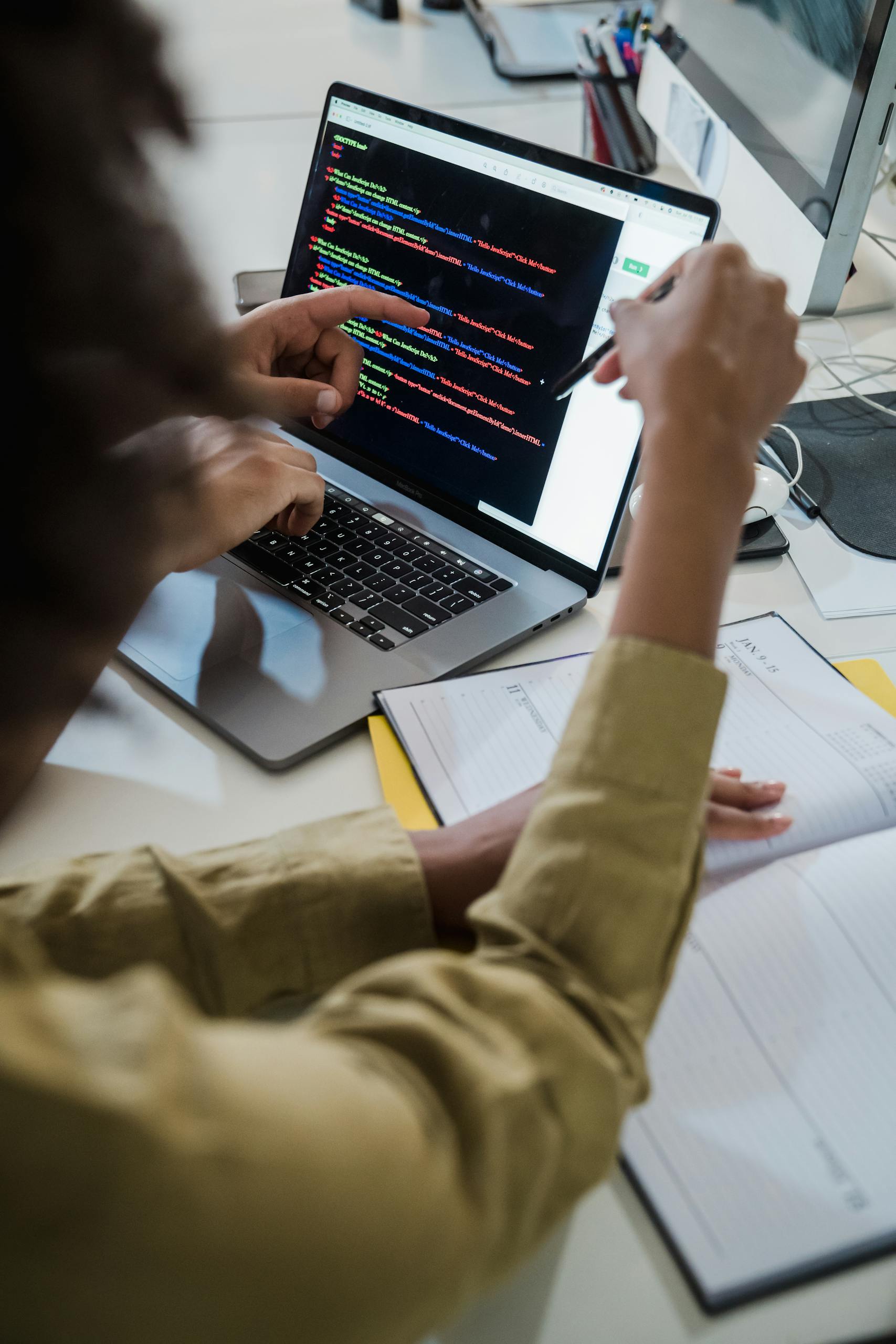 Two individuals discussing code on a laptop, focusing on web development.