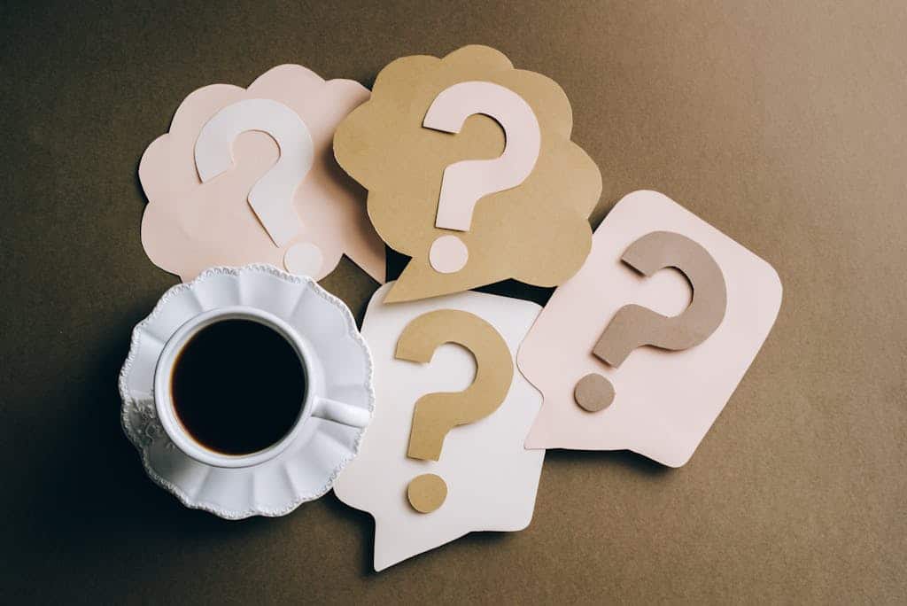 Creative concept with coffee cup and paper question marks on a table.